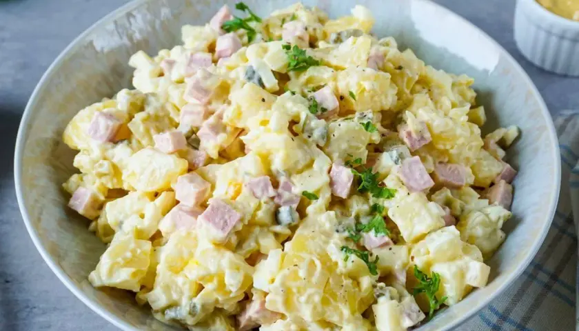 Ein Teller mit Omas Kartoffelsalat mit Mayonnaise, garniert mit Petersilie. Ein Klassiker, der immer schmeckt!