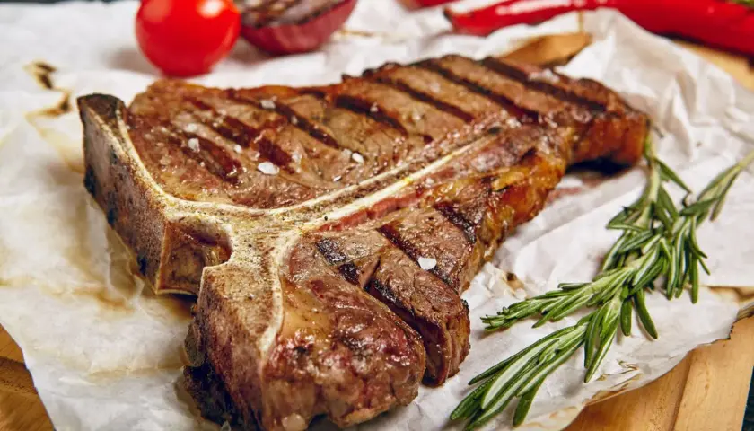 Perfekt gegrilltes T-Bone-Steak mit Rosmarin, Tomaten und Zwiebeln. Ein Genuss für jeden Grillmeister!