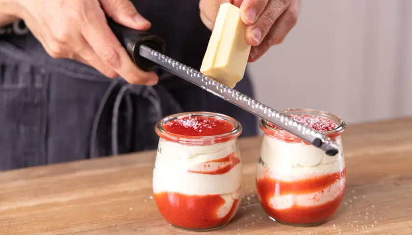 Zwei Gläser mit einem köstlichen Spaghetti Eis Dessert werden mit weißer Schokolade garniert.