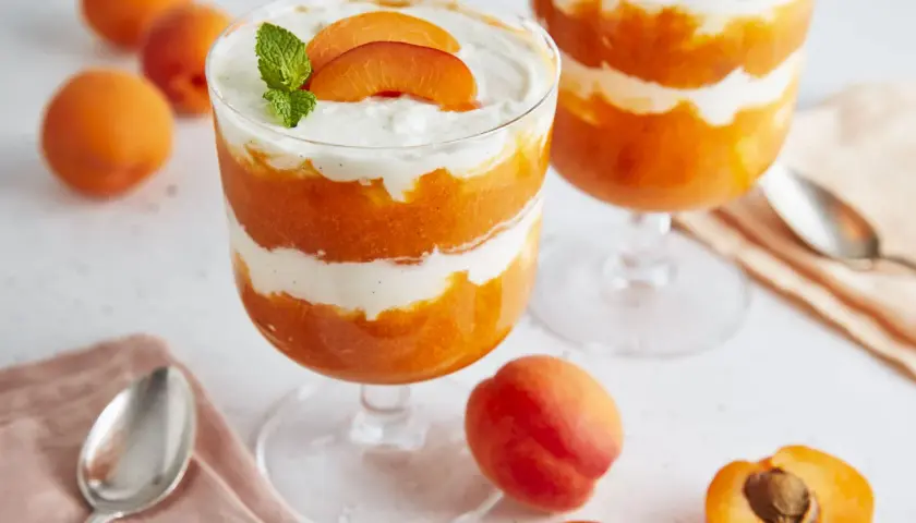 Schichtdessert mit Aprikosenpüree und Mascarponecreme, garniert mit frischen Aprikosenspalten und Minze.