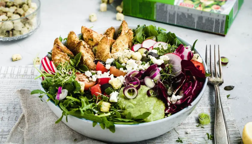 Bunter Salat mit knusprigen Kartoffelspalten, Feta, Radieschen und cremiger Avocado-Dip.