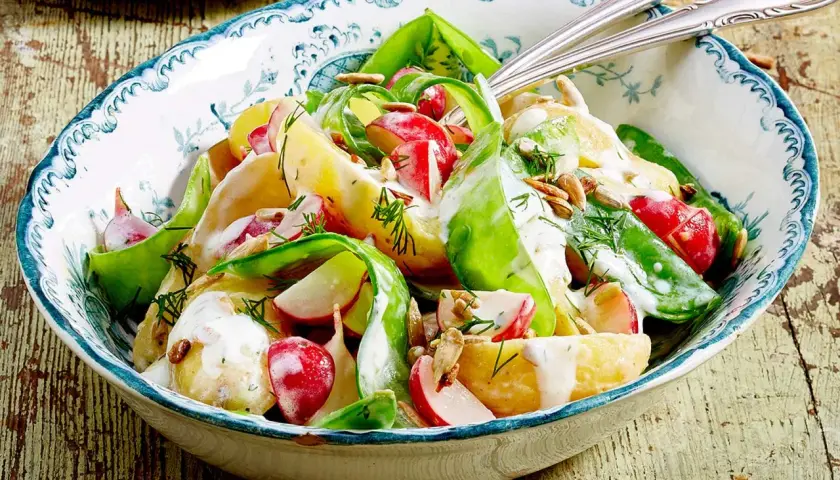 Kartoffelsalat mit Radieschen, Gurke und Dill, verfeinert mit einer cremigen Sauce und Sonnenblumenkernen. Ein frischer Genuss!