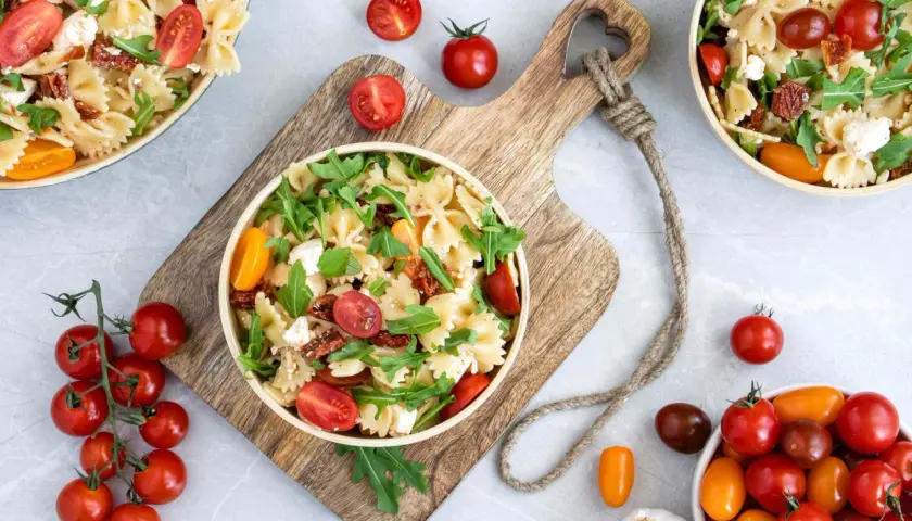 Ein köstlicher mediterraner Salat mit Farfalle, getrockneten Tomaten, frischen Kirschtomaten, Rucola und Feta.