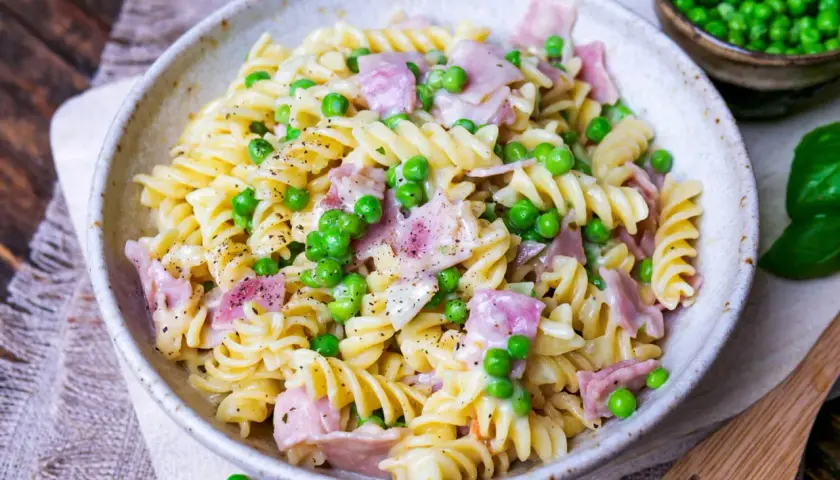 Fusilli-Nudeln mit Erbsen und Schinken in cremiger Schinken Sahne Sauce, bestreut mit schwarzem Pfeffer.