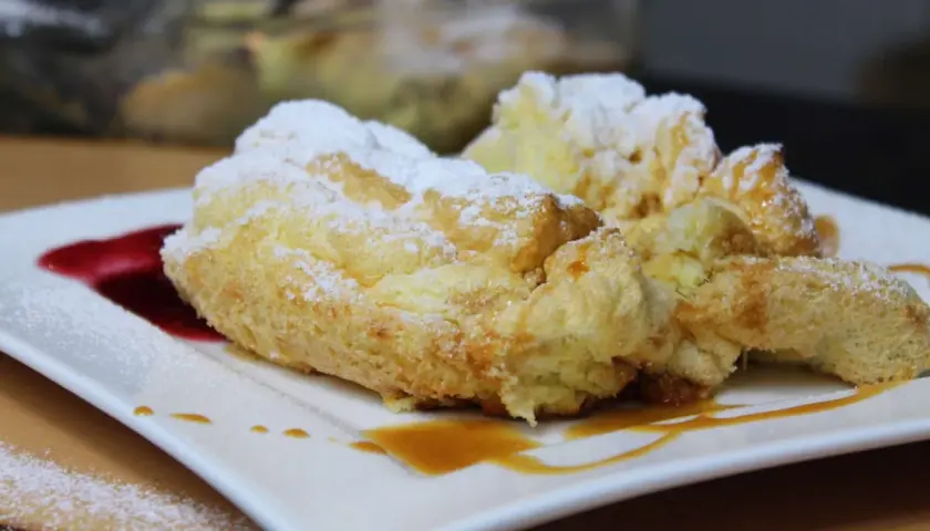 Perfekte Salzburger Nockerl, die nicht zusammenfallen, bestäubt mit Puderzucker und garniert mit Karamell und roter Sauce.