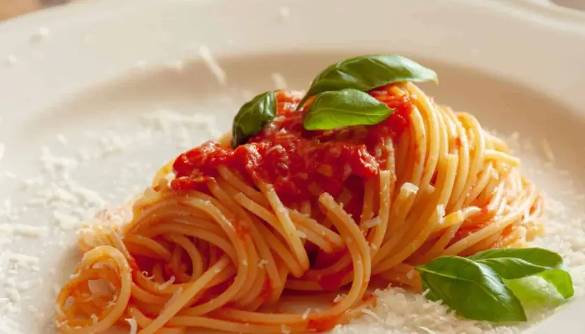 Ein Teller Spaghetti mit einer leckeren Tomatensauce, garniert mit frischem Basilikum und Parmesan. Ein Klassiker der italienischen Küche.