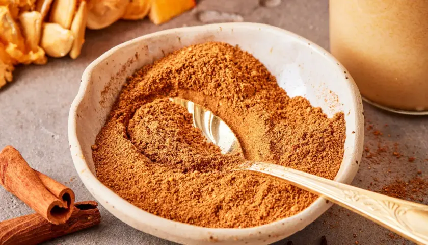 Schüssel mit Gewürzmischung zum Pumpkin Spice selber machen, daneben Zimtstangen, Nelken und Kürbiskerne.