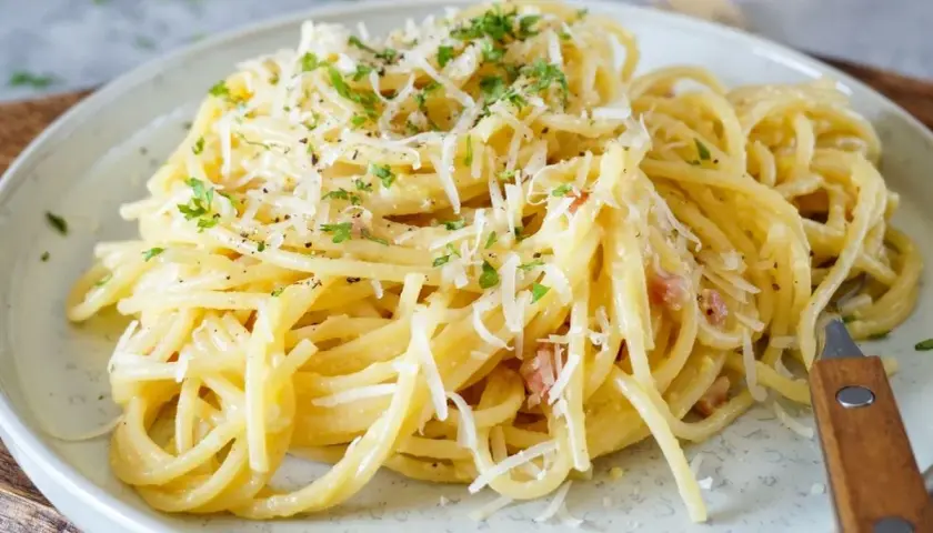Ein Teller cremiger Spaghetti Carbonara, garniert mit Parmesan und Petersilie. Perfekt für einfache spaghetti rezepte.
