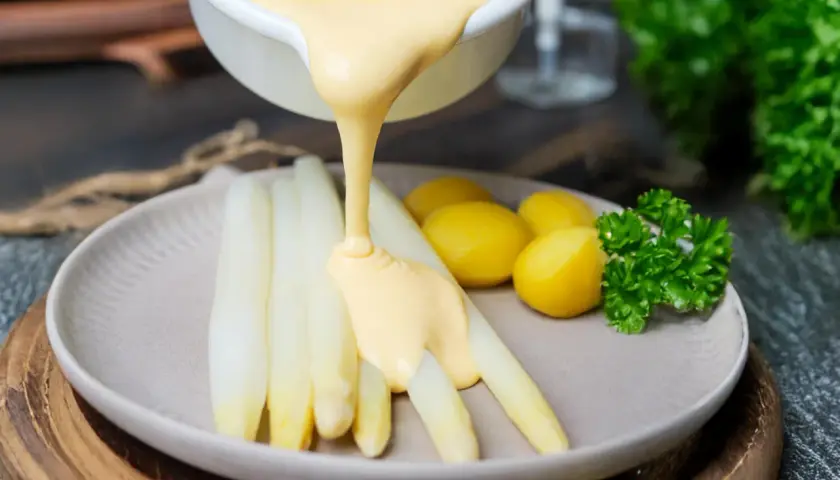Weißer Spargel mit kleinen Kartoffeln und Petersilie, übergossen mit cremiger Sauce Hollandaise.