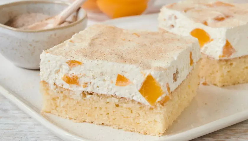 Saftiger Pfirsich Schmand Kuchen mit zarter Creme und Pfirsichstücken, bestreut mit Zimt. Ein Genuss!