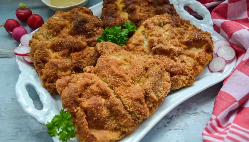 Goldbraun paniertes Schnitzel, perfekt zubereitet. Dazu Radieschen und Senf. Ein Genuss für jeden, der gerne Schnitzel paniert.