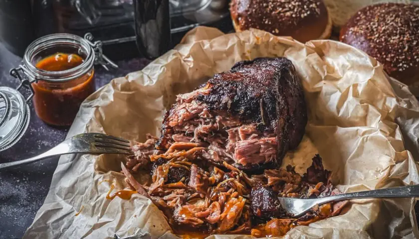 Pulled Pork aus dem Airfryer, saftig und zart, mit BBQ-Sauce beträufelt. Dazu passen die aufgeschnittenen Burgerbrötchen.