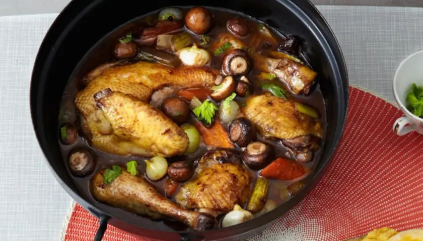 Coq au Riesling rezept original: Ein ganzer Brathähnchen-Mix mit Pilzen, Zwiebeln und Sellerie in dunkler Sauce.