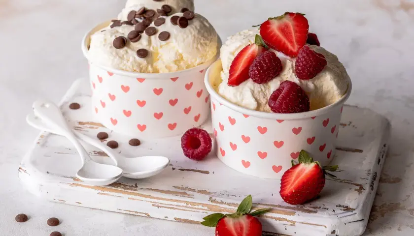 Zwei Becher mit cremigem Frozen Joghurt, einer mit Schokostückchen, der andere mit frischen Beeren. Ein leckeres Frozen Joghurt Rezept für heiße Tage.