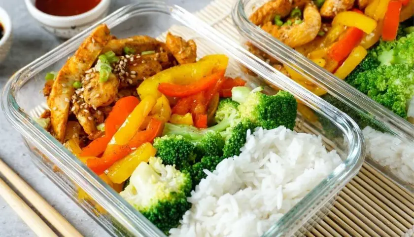 Gesunde meal prep rezepte: Hähnchen mit Paprika, Brokkoli und Reis in Glasbehältern. Perfekt für unterwegs.