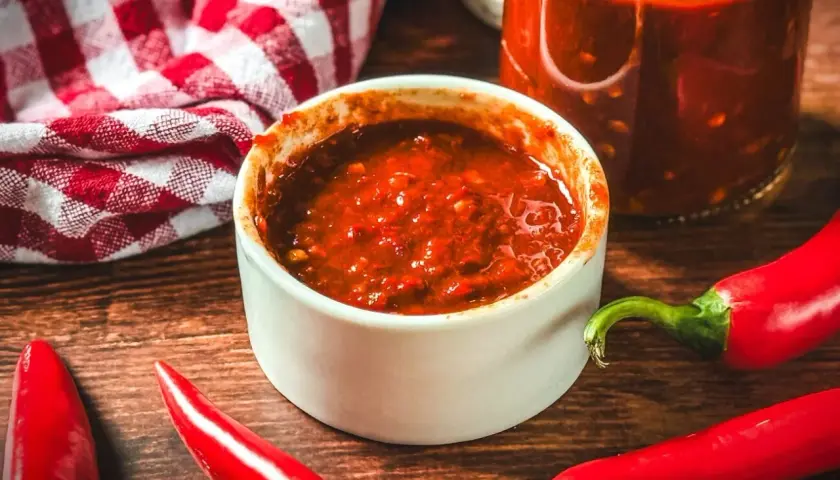 Selbstgemachte Chilipaste in einer Schale, umgeben von frischen Chilis. Perfekt, um dein Essen zu würzen!