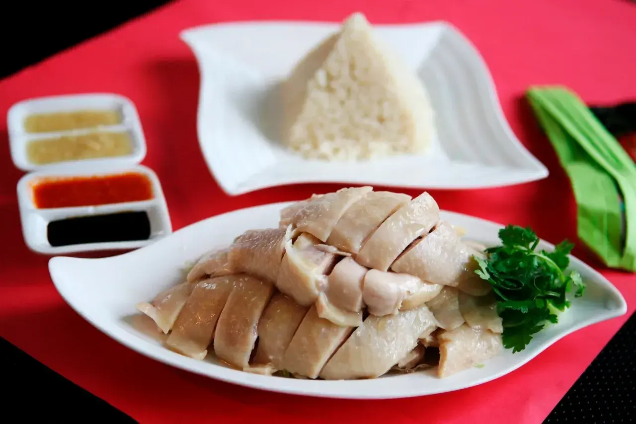 Zartes, geschnittenes Hähnchenfleisch mit duftendem Reis und Soßen – ein klassisches Hainanese Chicken Rice Gericht.