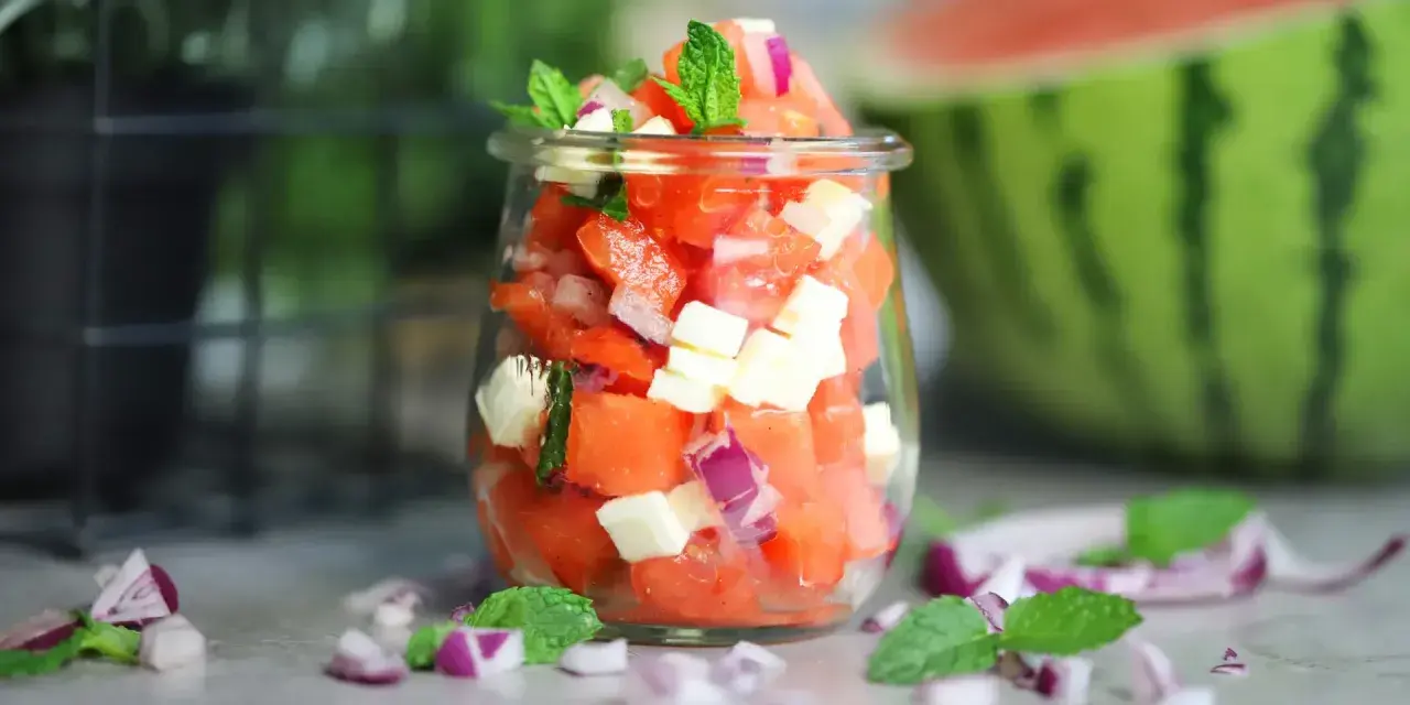 Erfrischender Wassermelonen Salat mit Feta, roten Zwiebeln und Minze in einem Glas. Perfekt für heiße Tage!