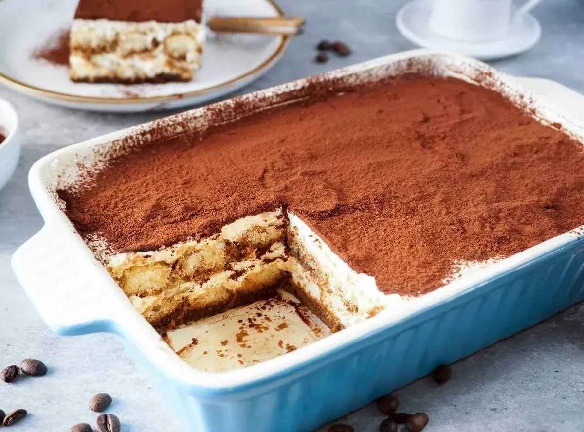 Ein köstliches Tiramisu mit Sahne und Mascarpone, bestäubt mit Kakao. Ein Stück wurde bereits entnommen.