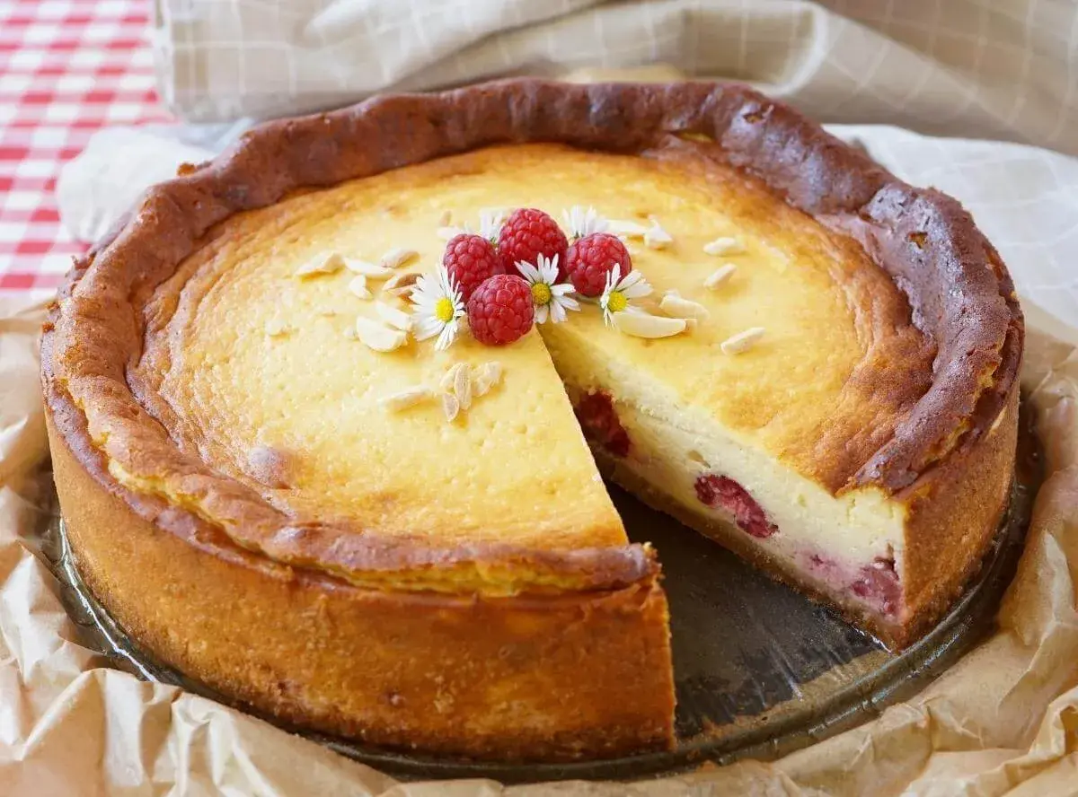 Ein köstlicher Kuchen mit Mascarpone und Himbeeren, garniert mit Mandelsplittern und frischen Beeren.