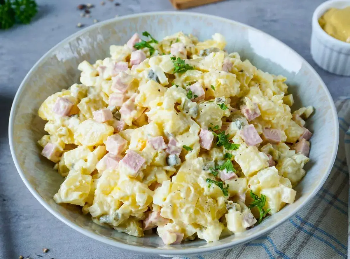 Ein Teller mit Omas Kartoffelsalat mit Mayonnaise, garniert mit Petersilie. Ein Klassiker, der immer schmeckt!