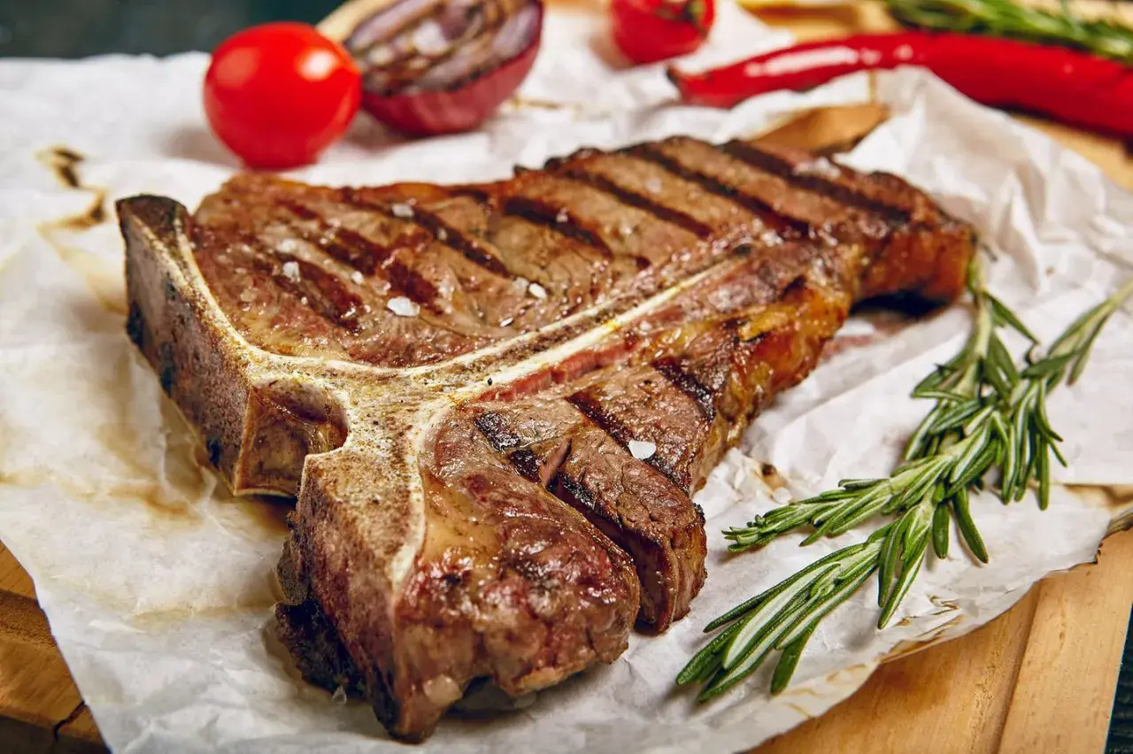 Perfekt gegrilltes T-Bone-Steak mit Rosmarin, Tomaten und Zwiebeln. Ein Genuss für jeden Grillmeister!