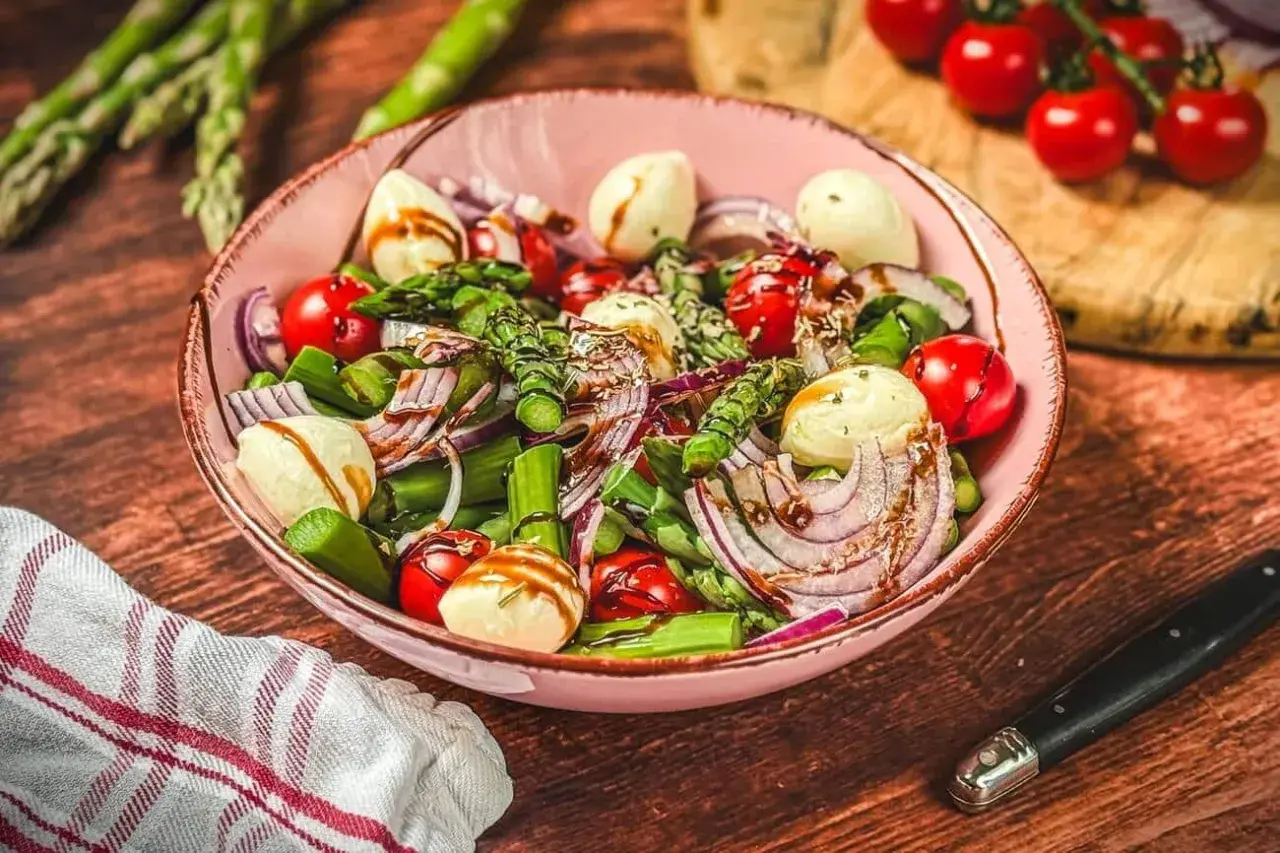 Ein frischer Spargel Tomaten Salat mit Mozzarella und roten Zwiebeln, beträufelt mit Balsamico.