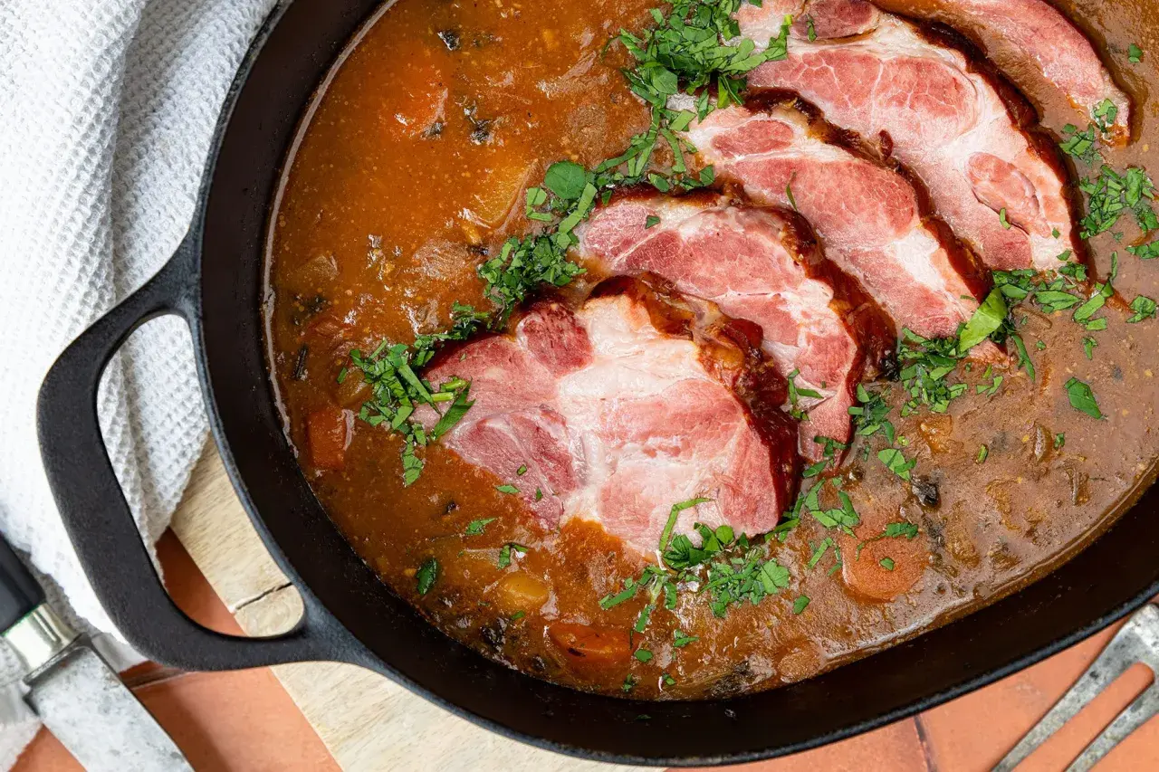 Gegarter Kassler in Scheiben in einer deftigen Soße, garniert mit Petersilie. Die Frage "wie lange braucht 1 kg Kassler im Backofen" beschäftigt viele Hobbyköche.