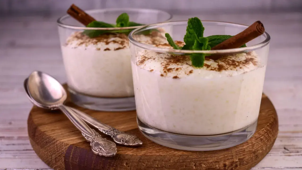 Zwei Gläser cremiger Milchreis, garniert mit Zimt und Minze. Ein einfaches Milchreis Rezept, das süße Erinnerungen weckt.