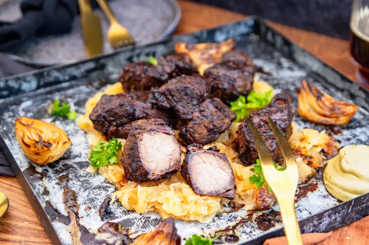 Herzhaftes Mutzbraten Rezept Original: Dunkles, saftiges Fleisch auf Sauerkraut, garniert mit Petersilie und gerösteten Zwiebeln. Ein Festmahl!