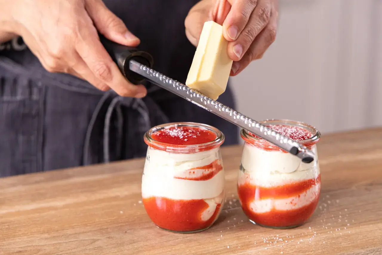 Zwei Gläser mit einem köstlichen Spaghetti Eis Dessert werden mit weißer Schokolade garniert.