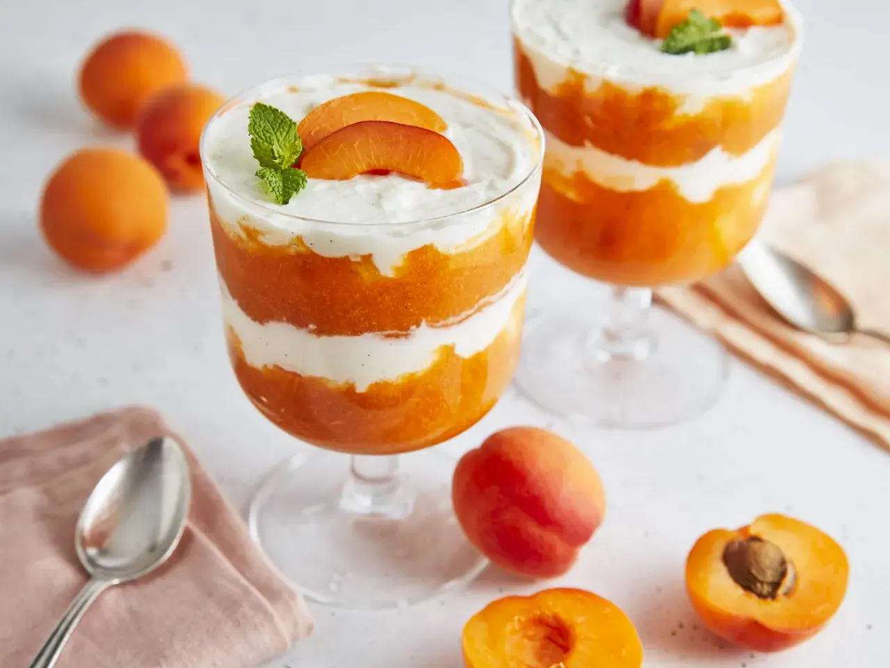 Schichtdessert mit Aprikosenpüree und Mascarponecreme, garniert mit frischen Aprikosenspalten und Minze.