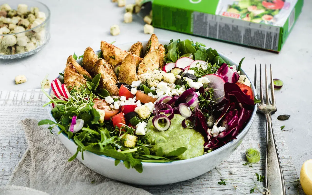 Bunter Salat mit knusprigen Kartoffelspalten, Feta, Radieschen und cremiger Avocado-Dip.