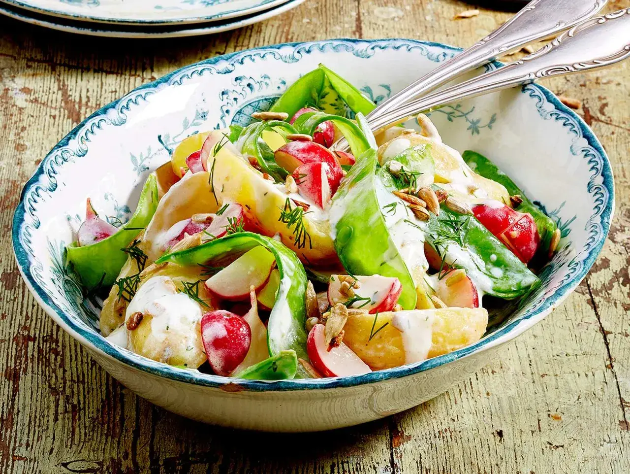 Kartoffelsalat mit Radieschen, Gurke und Dill, verfeinert mit einer cremigen Sauce und Sonnenblumenkernen. Ein frischer Genuss!