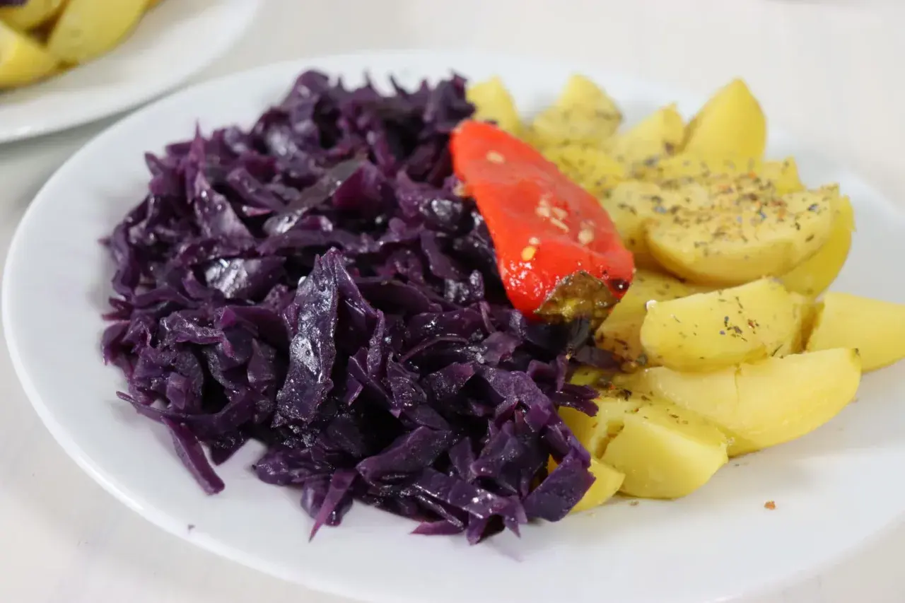 Rotkohl-Rezepte mal anders: Ein Teller mit deftigem Rotkohl, Kartoffelspalten und einer roten Paprika.