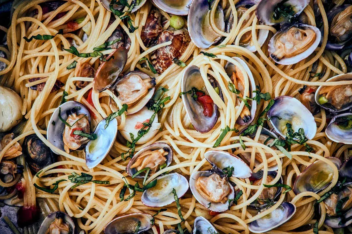 Spaghetti mit Muscheln, ein köstliches Gericht mit zarten Muscheln und perfekt gekochten Nudeln, garniert mit frischen Kräutern.
