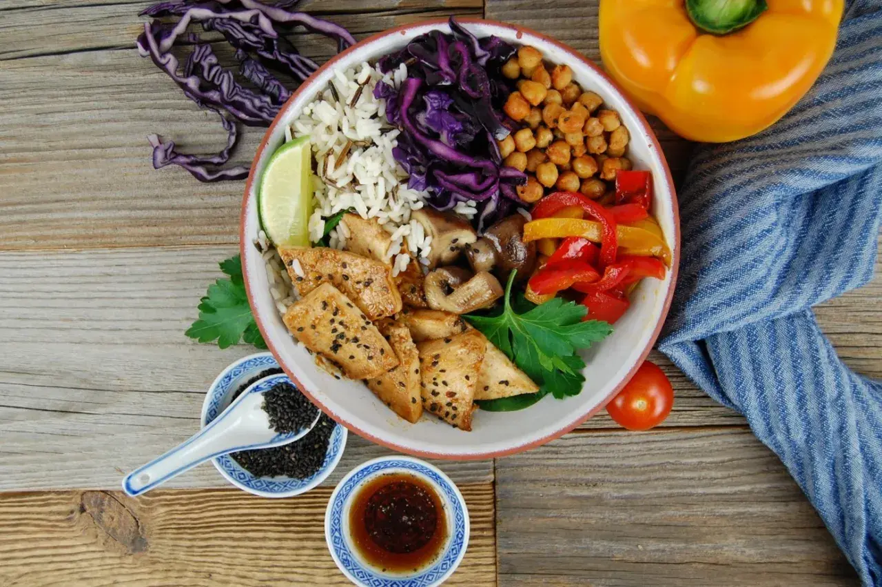 Bunter Bowl mit Reis, Hähnchen, Gemüse und Kichererbsen. Perfekt, um eine leckere bowl sauce selber machen.