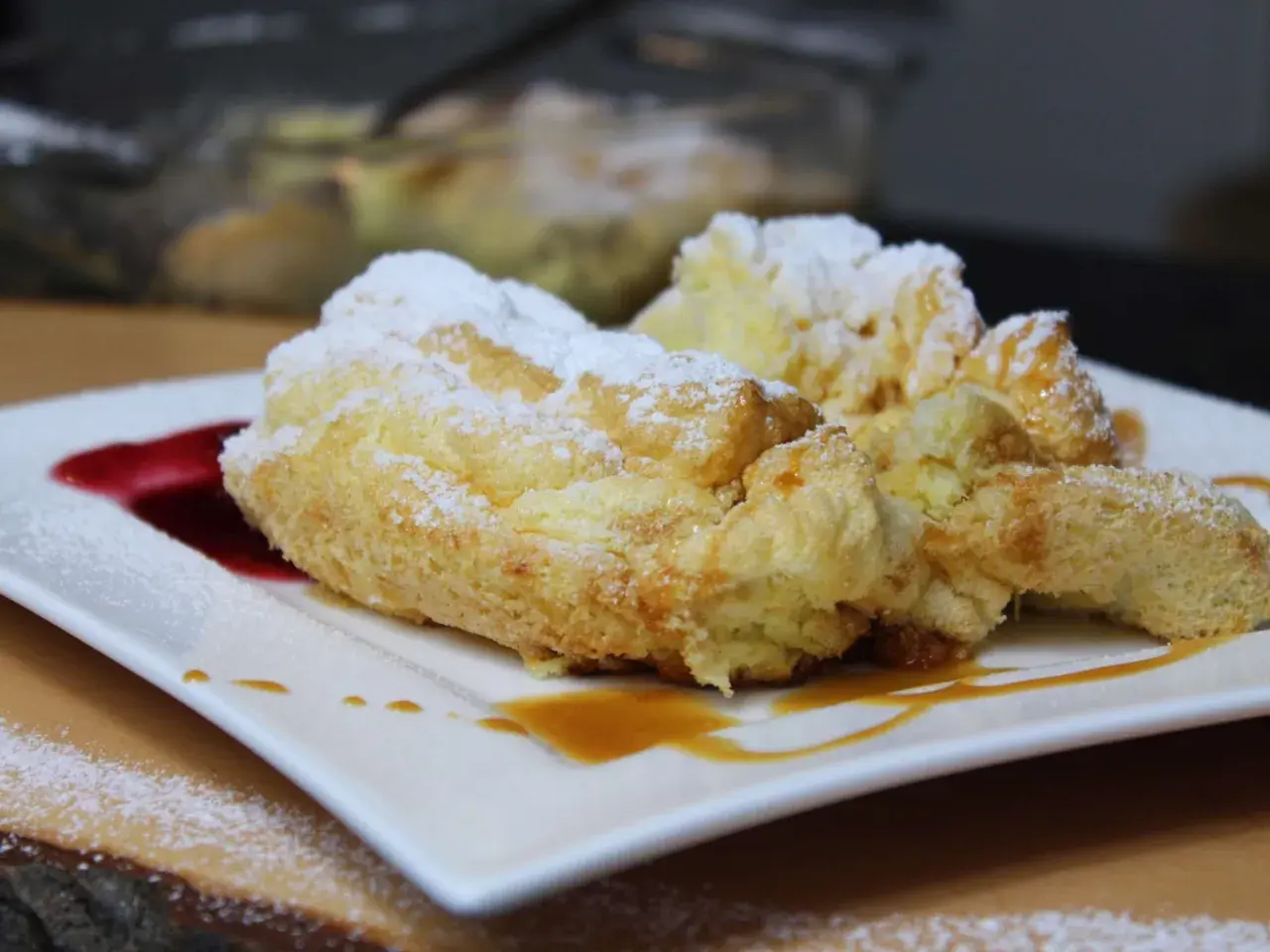 Perfekte Salzburger Nockerl, die nicht zusammenfallen, bestäubt mit Puderzucker und garniert mit Karamell und roter Sauce.