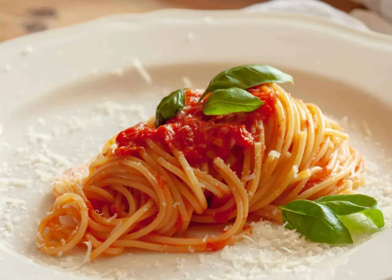 Ein Teller Spaghetti mit einer leckeren Tomatensauce, garniert mit frischem Basilikum und Parmesan. Ein Klassiker der italienischen Küche.