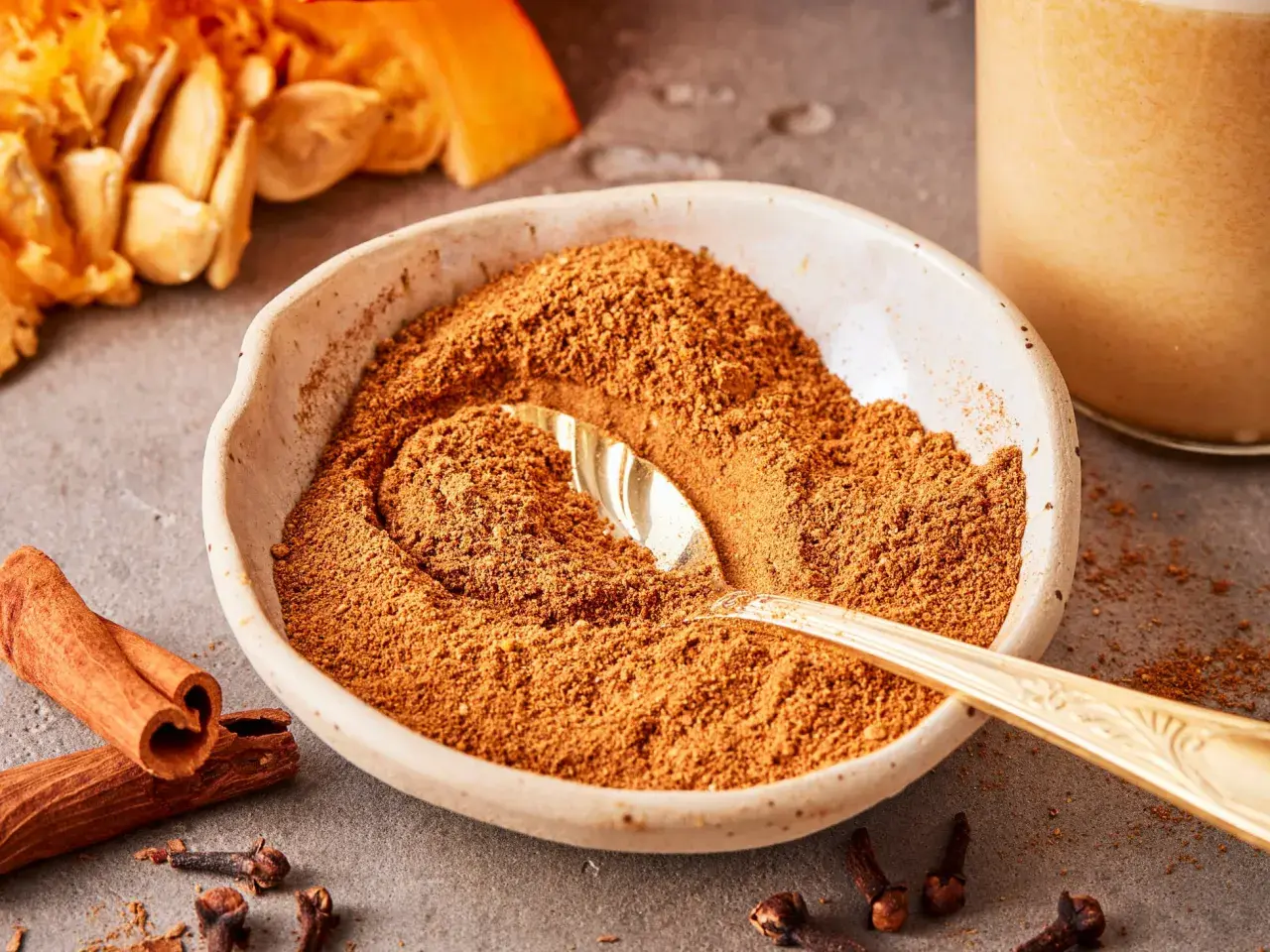 Schüssel mit Gewürzmischung zum Pumpkin Spice selber machen, daneben Zimtstangen, Nelken und Kürbiskerne.
