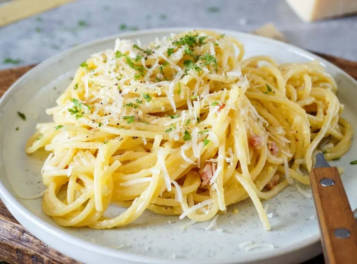 Ein Teller cremiger Spaghetti Carbonara, garniert mit Parmesan und Petersilie. Perfekt für einfache spaghetti rezepte.