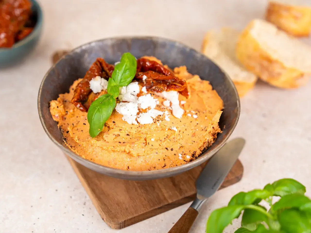 Ein cremiger Tomaten Feta Dip, garniert mit getrockneten Tomaten und Basilikum. Perfekt zum Dippen mit Brot.