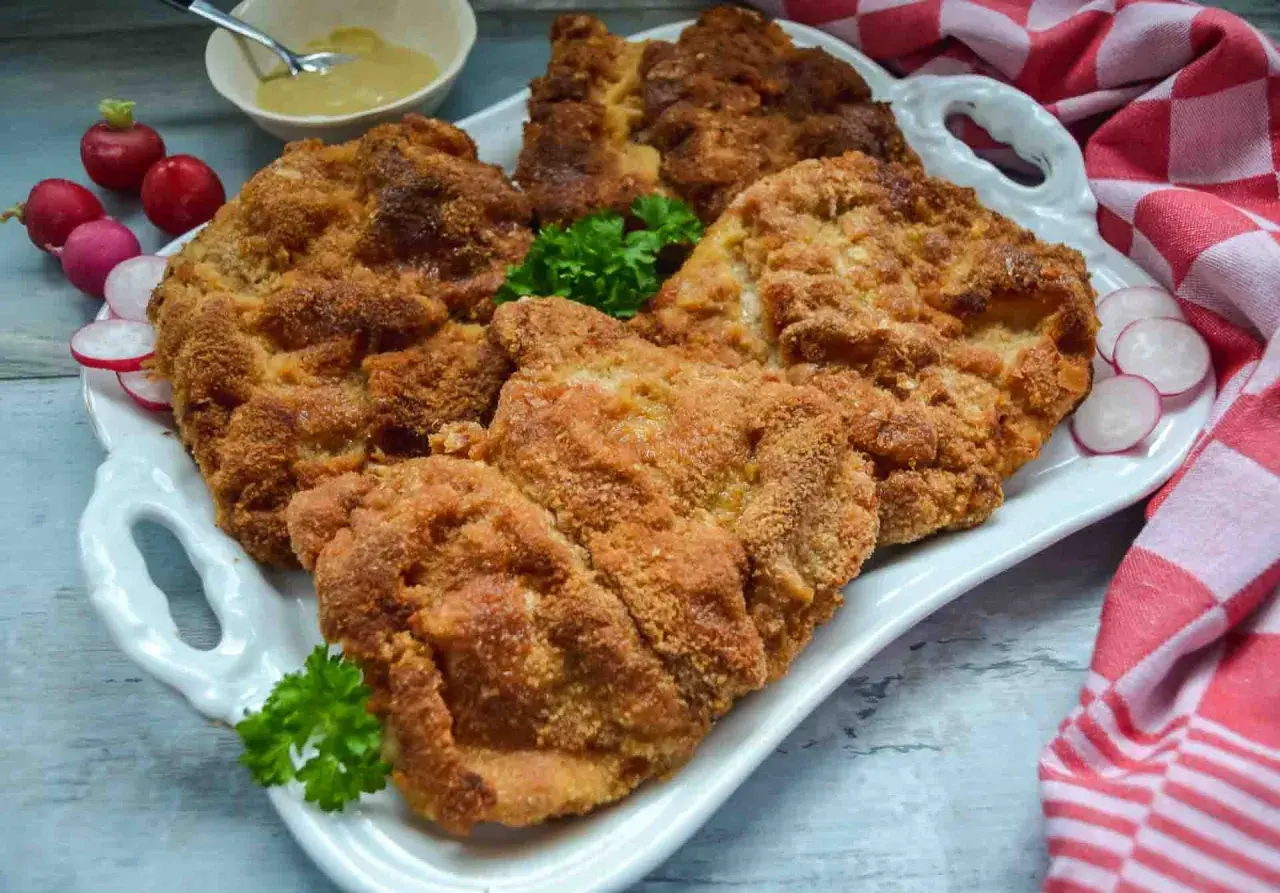 Goldbraun paniertes Schnitzel, perfekt zubereitet. Dazu Radieschen und Senf. Ein Genuss für jeden, der gerne Schnitzel paniert.