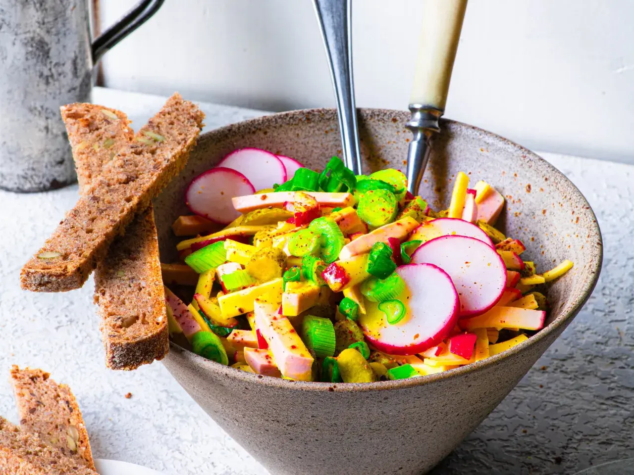 Schmackhafter Schweizer Wurstsalat mit Radieschen und Lauchzwiebeln, serviert mit Vollkornbrot. Ein tolles Rezept für den Sommer!