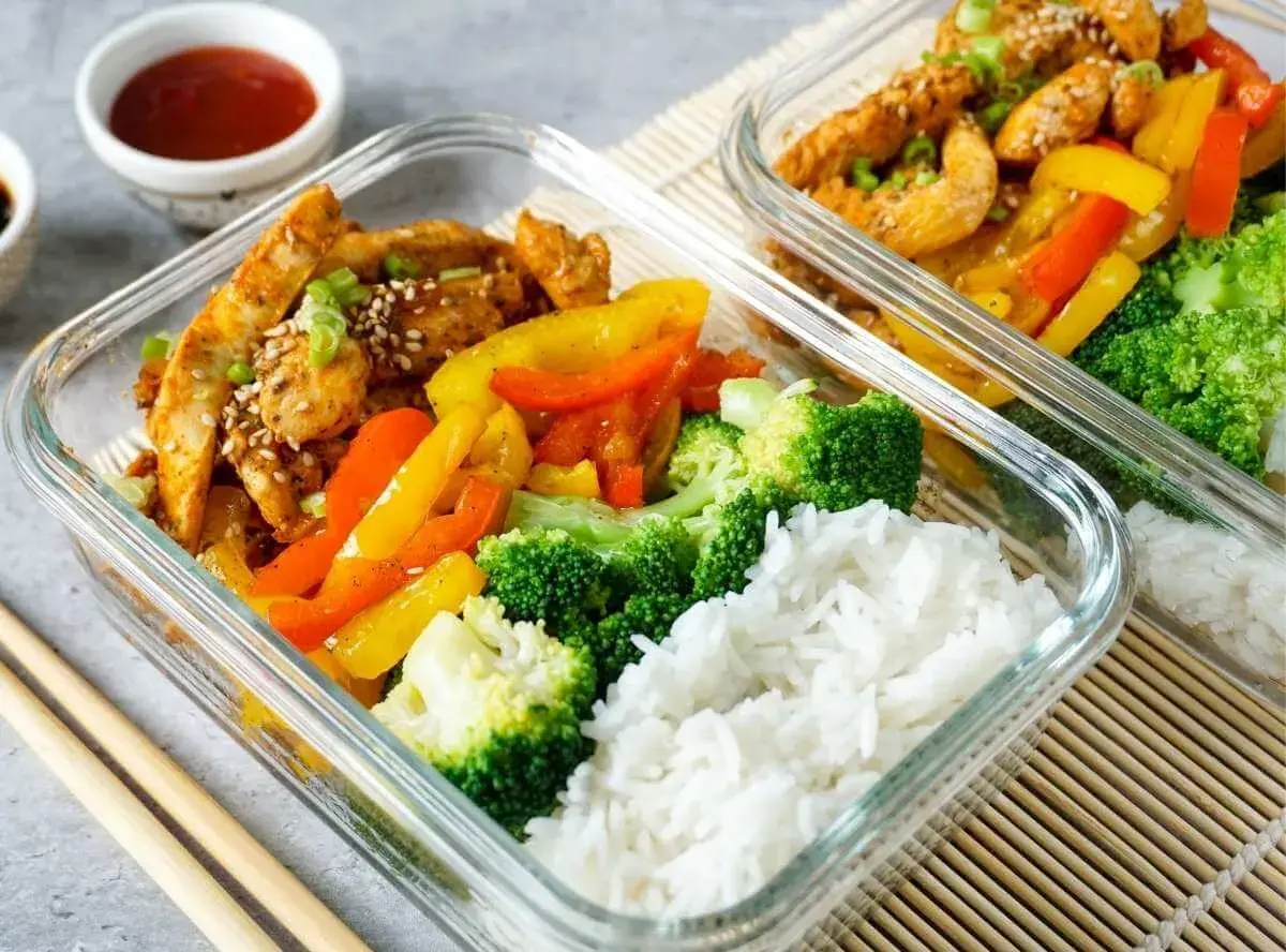 Gesunde meal prep rezepte: Hähnchen mit Paprika, Brokkoli und Reis in Glasbehältern. Perfekt für unterwegs.