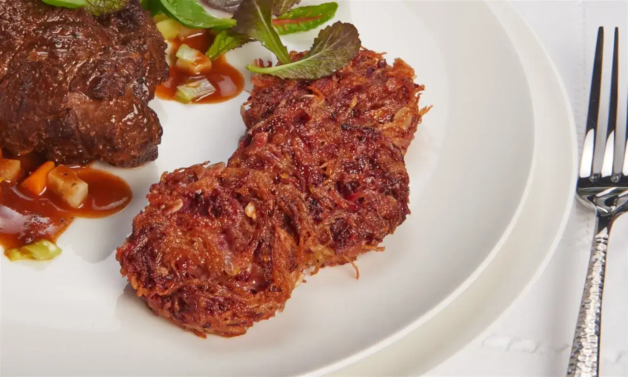 Knusprige rote Bete Puffer paniert, serviert mit einem Stück Fleisch und Sauce.