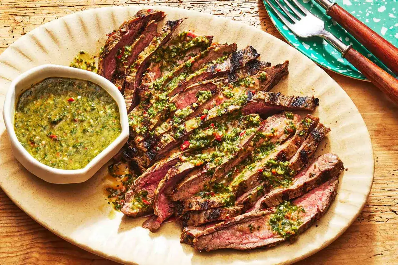 Saftiges, gegrilltes Steak, in Scheiben geschnitten und mit frischem Chimichurri-Rezept beträufelt, serviert mit einer Schüssel der grünen Sauce.