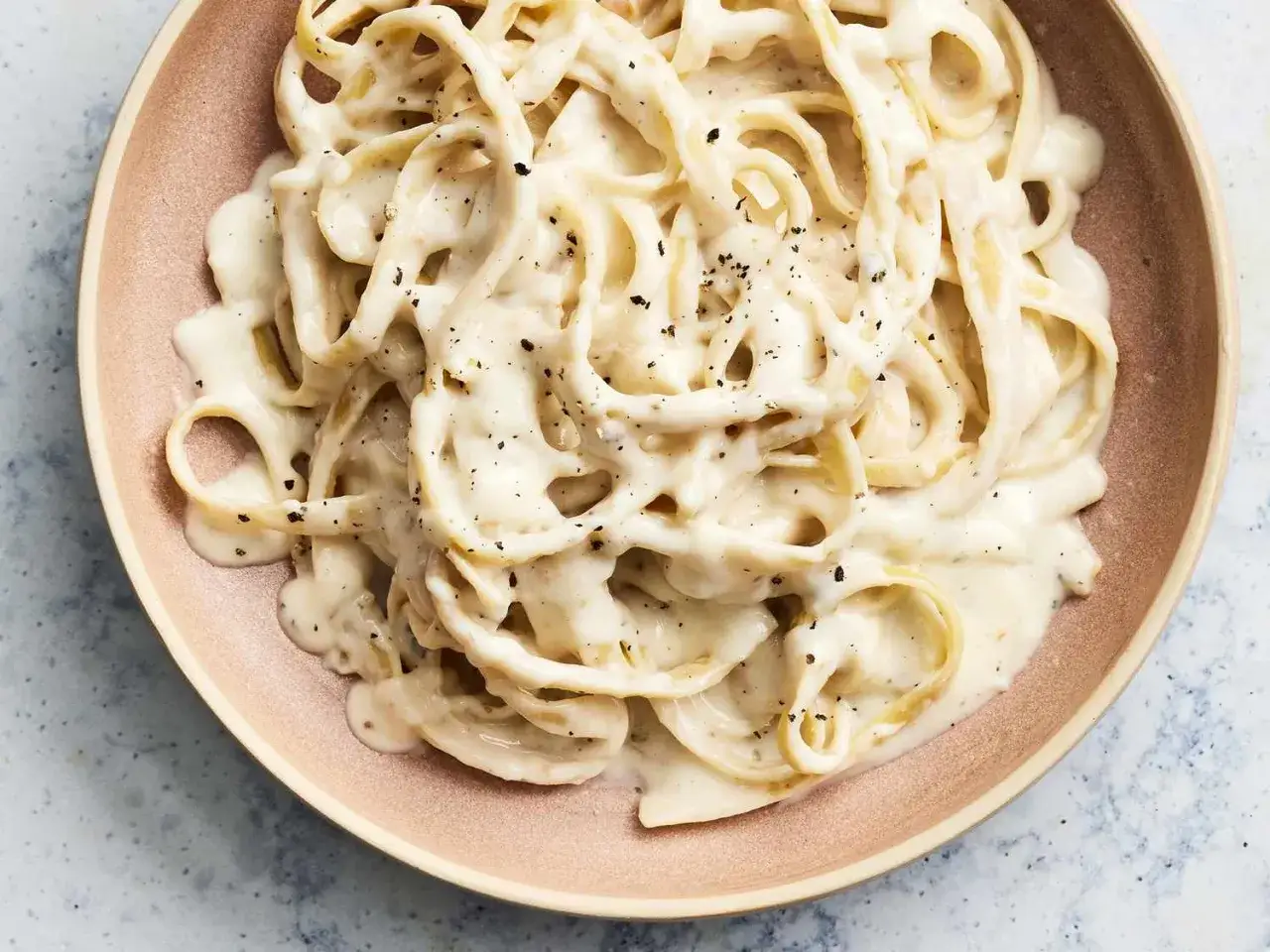 Cremige Pasta Alfredo, ein einfaches und köstliches Pasta alfredo rezept, serviert auf einem rosafarbenen Teller.