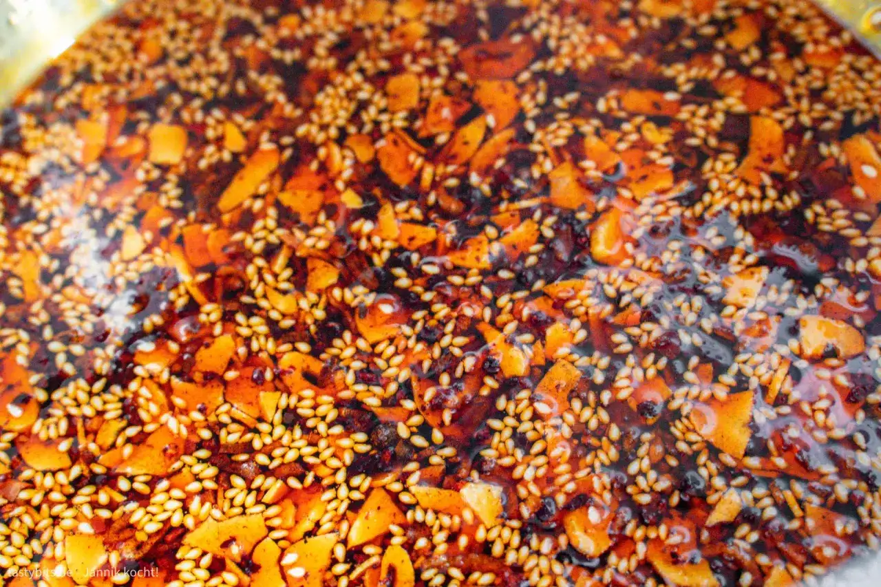 Ein köstliches, selbstgemachtes Crispy Chili Oil Rezept mit gerösteten Sesamsamen und Chili-Flocken in heißem Öl.