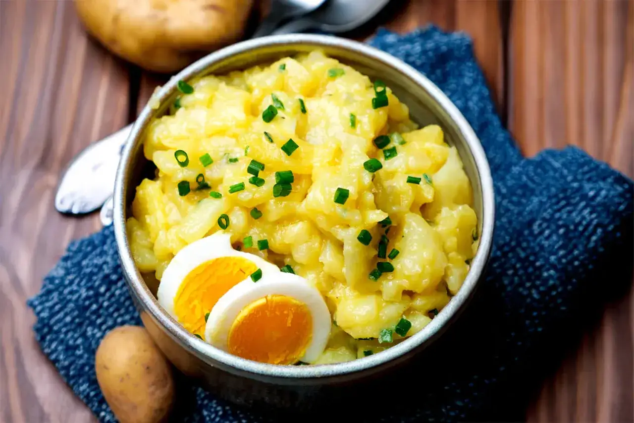 Schüssel mit deutschem Kartoffelsalat, garniert mit Schnittlauch und gekochten Eiern. Ein Klassiker, der immer schmeckt.